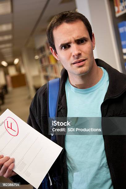 Upset College Student In Library Holding F Grade On Exam Stock Photo - Download Image Now