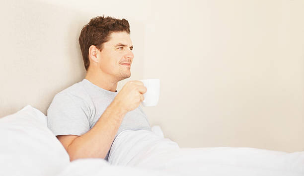 istock Young man holding coffee cup in bed 182387532