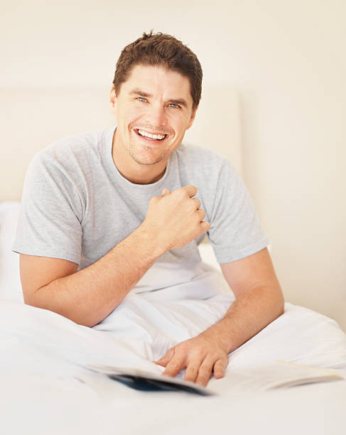 istock Happy young man with a book in bed 182387540