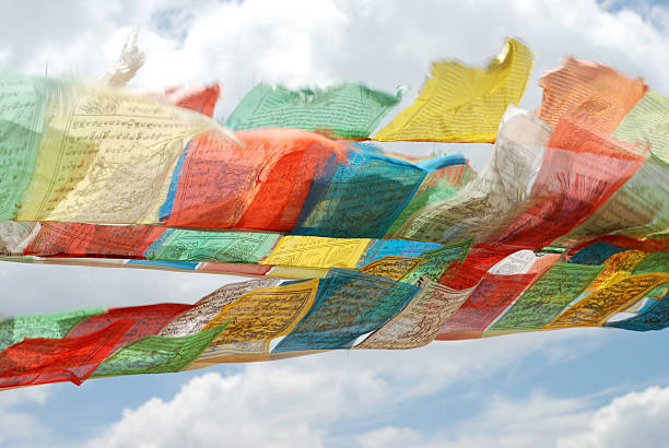 Old Tibetan Prayer Flags flying against a cloudy sky stock photo