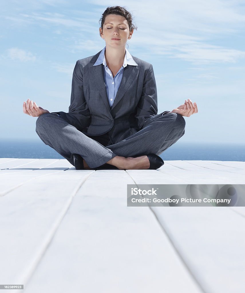 Adulto di mezza età donna d'affari seduto nella posizione del loto all'aperto - Foto stock royalty-free di Completo