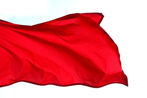 Red Flag floating in the wind isolated on white background.