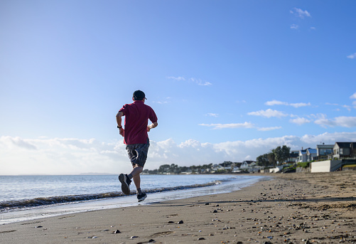 Man running on the beach in the morning. Milford beach. Auckland.