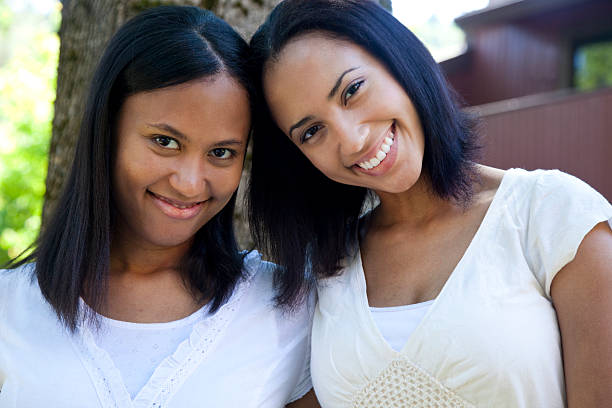 two young women sisters smiling at camera outdoors