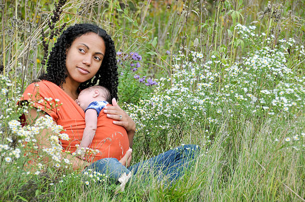 Young Mother cradles her son in a field of flowers