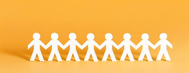 Community concept Paper people standing in a row holding hands. Banner format. line of people holding hands stock pictures, royalty-free photos & images