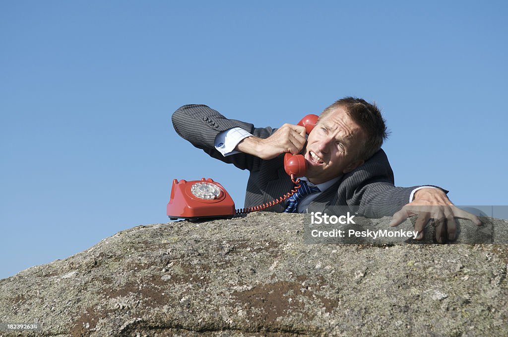 Desperate ビジネスマ�ンの電話での崖から岩 - 落ちるのロイヤリティフリーストックフォト