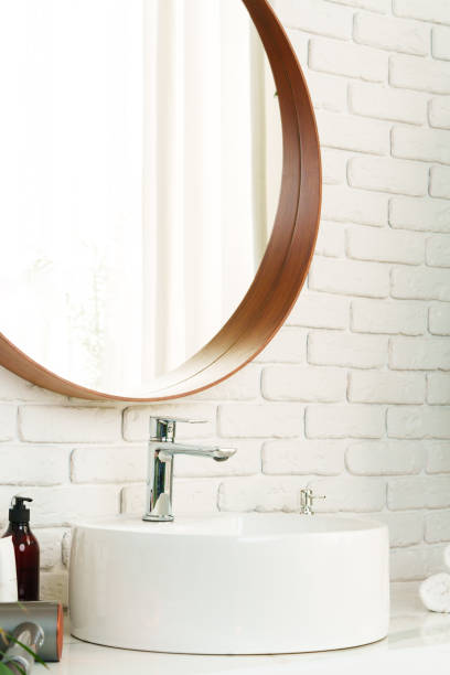 istock Bathroom interior with circle shaped mirror in wooden frame and white sink 1823928537