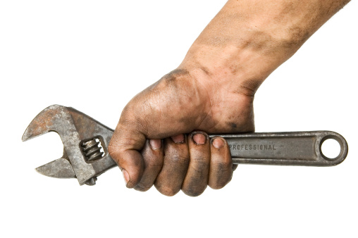greasy hand holding an adjustable wrench on white background.