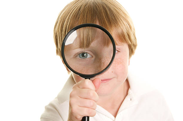 istock Cute Little Boy Looking Through a Magnifying Glass 182392911