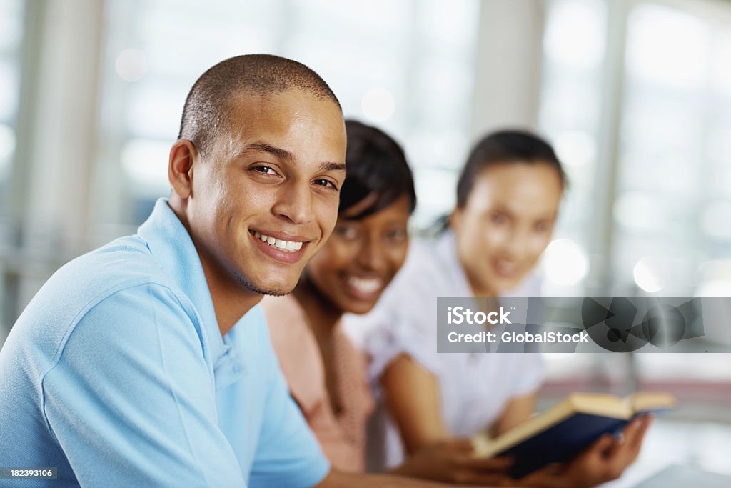 Giovane uomo sorridente accanto ai suoi amici - Foto stock royalty-free di Libro