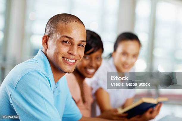 Giovane Uomo Sorridente Accanto Ai Suoi Amici - Fotografie stock e altre immagini di Libro - Libro, Sorridere, Studente universitario