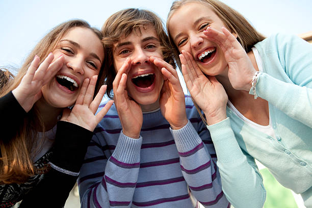 Happy indian group of friends wearing winter clothes shouting having fun isolated on grey background.