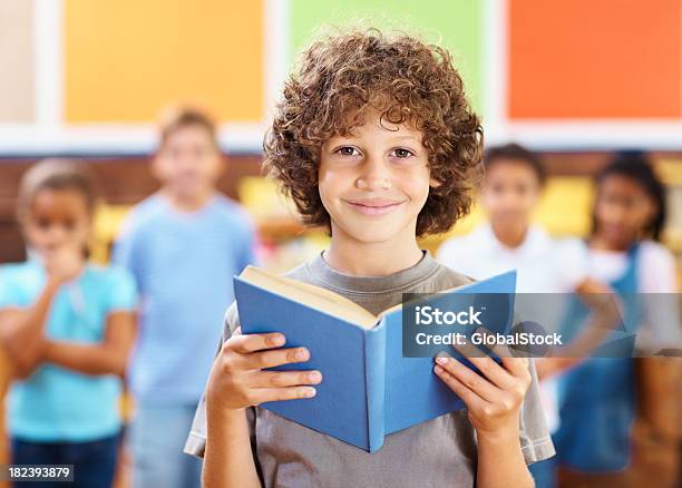 School Boy Retención Libro Con Amigos En El Fondo Foto de stock y más banco de imágenes de 8-9 años - 8-9 años, Agarrar, Amistad