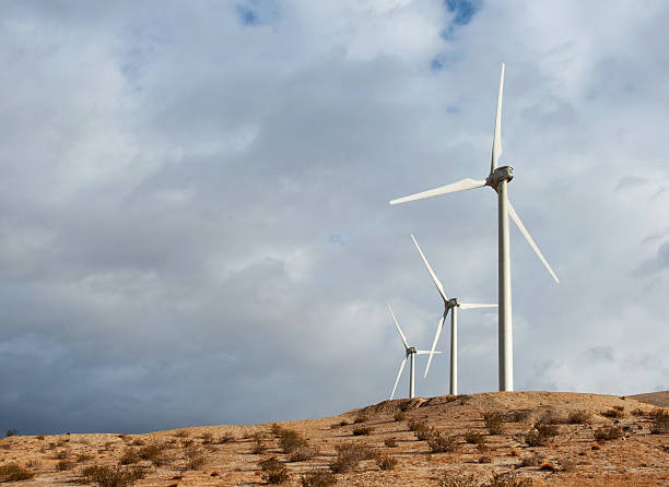 Three Power Generating Wind Turbines Behind Desert Ridge stock photo