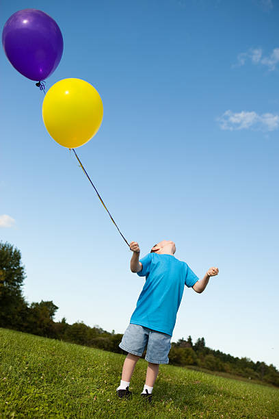 istock Happy Young Boy Holding Balloons Outside 182394242