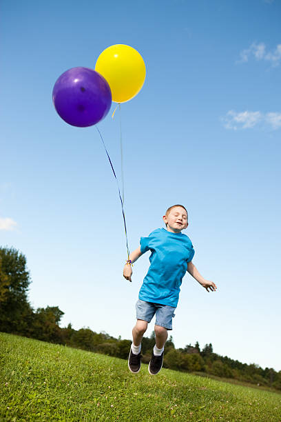 istock Happy Young Boy Jumping with Balloons Outside 182394247