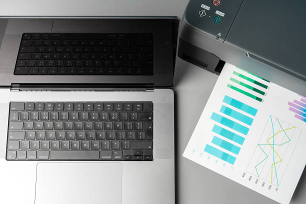 istock Modern printer with paper and laptop on table in office 1823955828