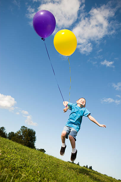 istock Carefree Young Boy Jumping with Balloons Outside 182396017