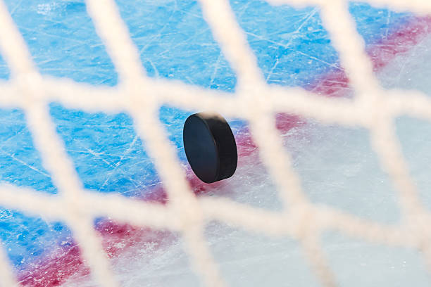 istock Hockey puck through goal net 182396300