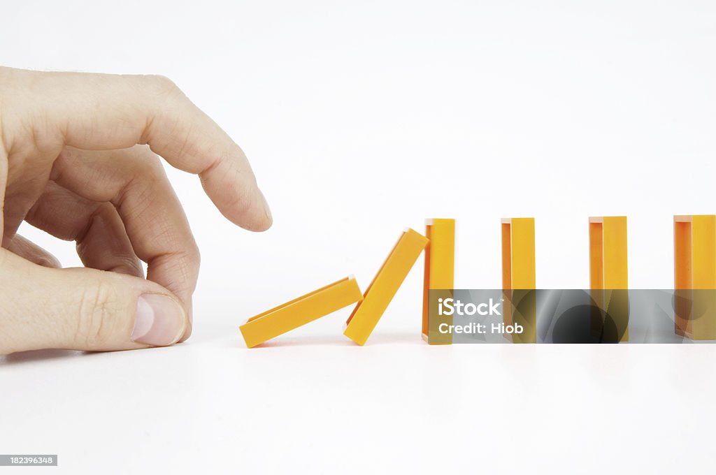 hand pushing dominoes Domino Effect Stock Photo