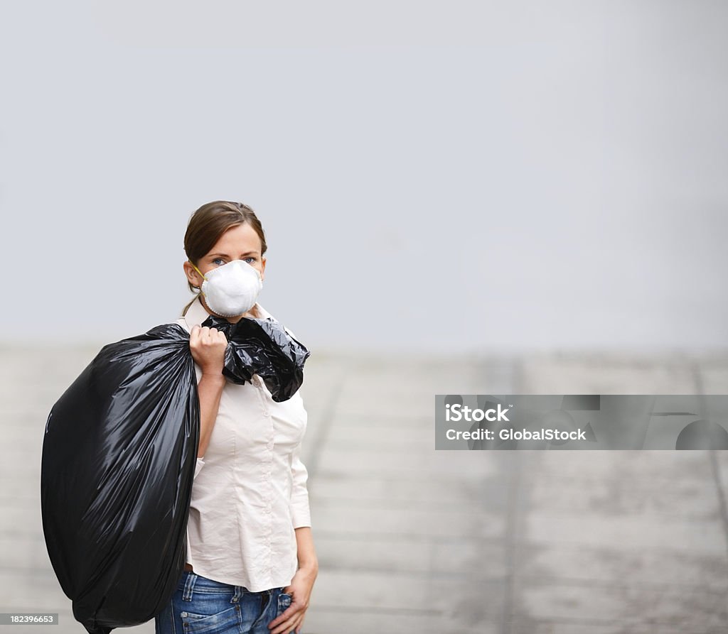 Молодая женщина в пыли маска держит Мешок для мусора - Стоковые фото 20-24 года роялти-фри