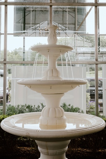A stunning view of an elegant white fountain in front of a large window