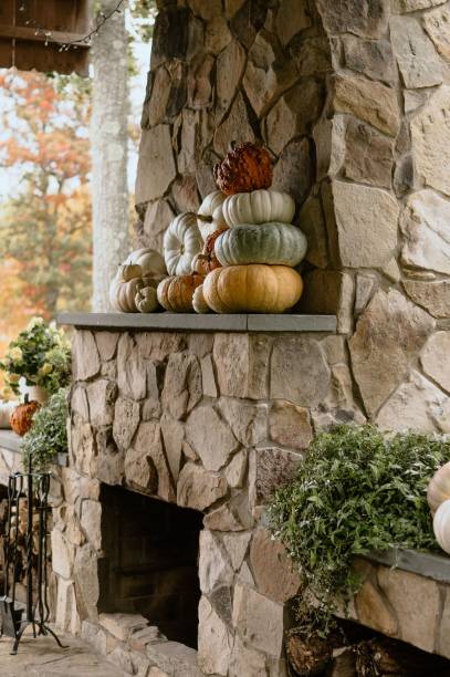 istock Cozy autumn scene with several large white and orange pumpkins on display in a stone fireplace 1823971059
