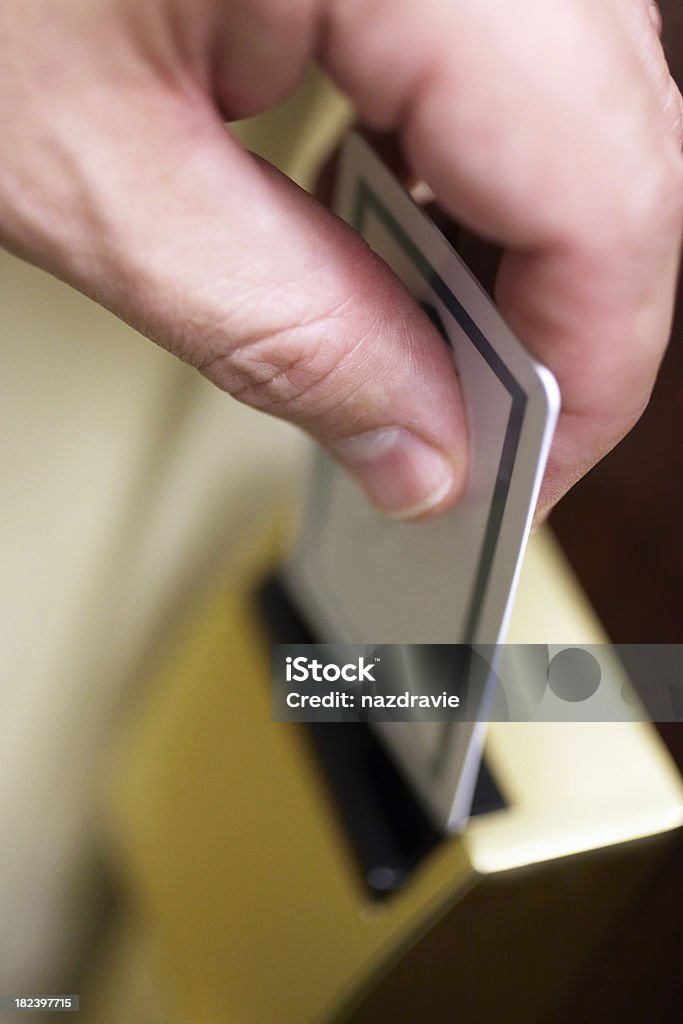 Hand Inserting Key Card Into Hotel Room Door Electronic Lock Vertical stock photo close-up of a male hand inserting a key card into a hotel room electronic lock to unlock the door. Adult Stock Photo