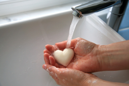 Woman washing her hands with a heart shaped soap.