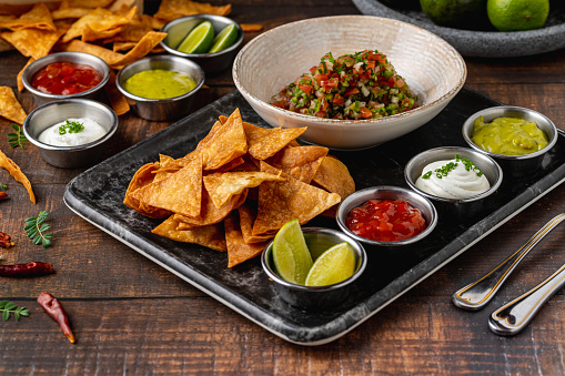 Pico de gallo from Mexican cuisine with dipping sauces on wooden table