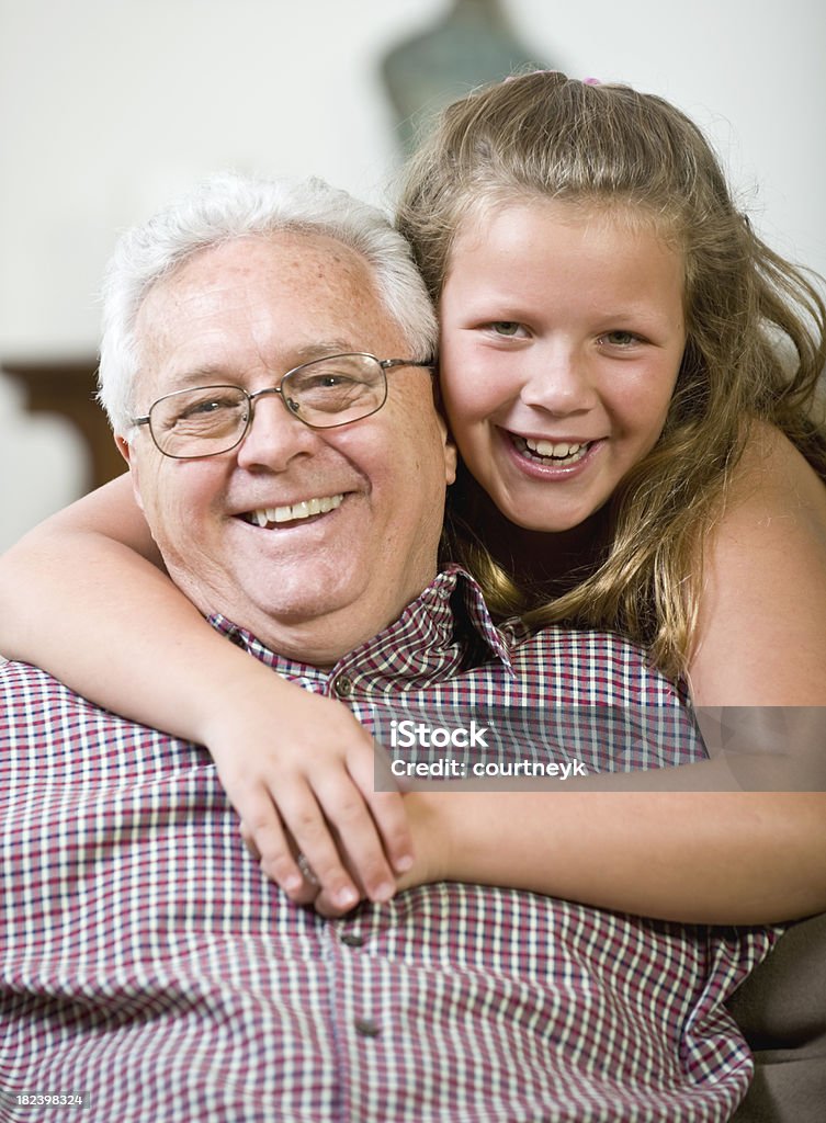 Dziadek uśmiech jest hugged jego grandaughter - Zbiór zdjęć royalty-free (Aktywni seniorzy)