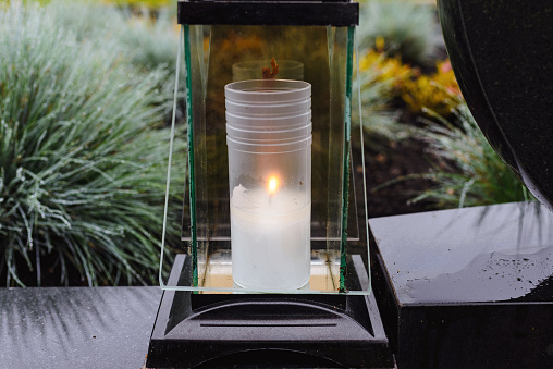 Grave candle light.Graves in a cemetery.Catholic cemetery background. All saints holiday.Grave candles on marble tomb.Gray granite grave.