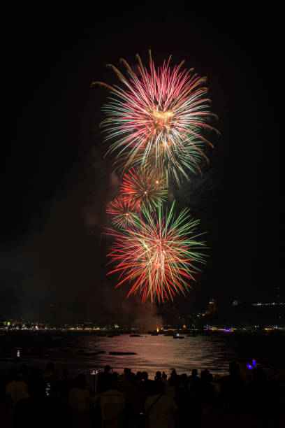 海辺の人々と街の常夜灯の背景とカラフルな花火のお祝い。 - fire firework display new year ストックフォトと画像