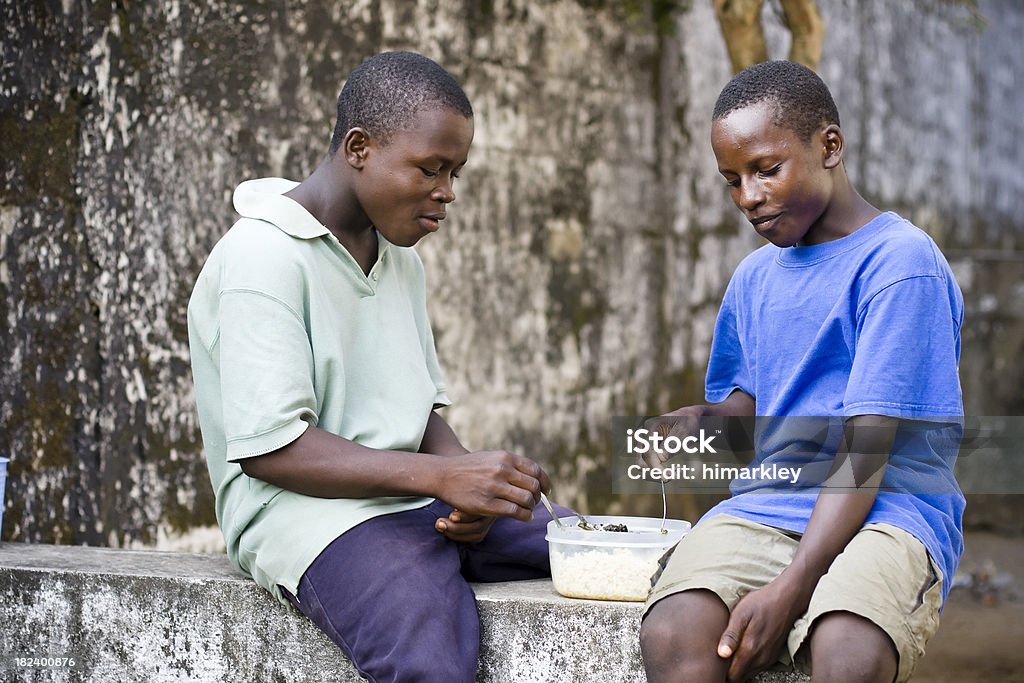 African Teens Eating Two African teen boys eating rice. Cousin Stock Photo