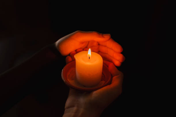 istock boy holds in a hand a burning candle against black background.Religious concept. 1824009540