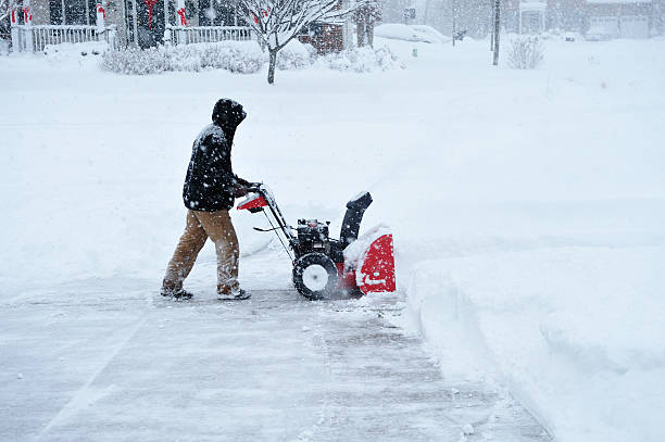 A red snowblower removing snow from a laneway blows the snow onto snowbanks.