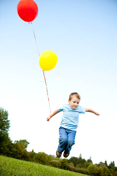 istock Happy Young Boy Jumping with Balloons Outside 182401457