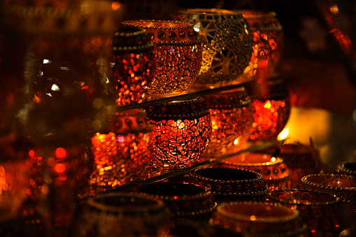Candle light in clear glass jar on wooden table background.