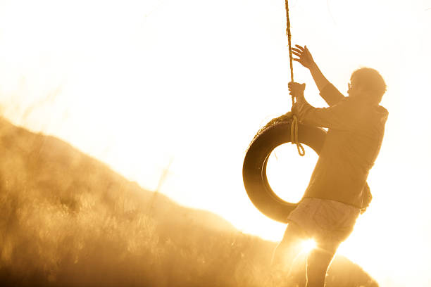 jovem hipster balançar de baloiço de corda ao pôr do sol - men swing tire rope swing imagens e fotografias de stock