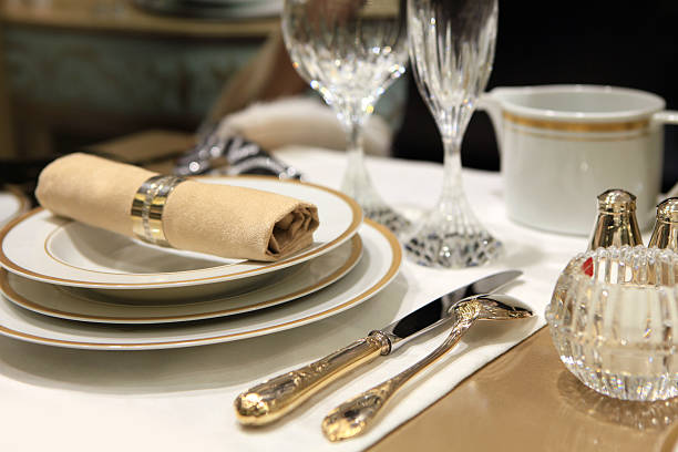 A table setting of fine china and crystal with beige linens stock photo