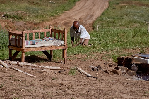 asuan, Egypt – October 28, 2023: A man working in a rural field near an old wooden bench in Asuan, Egypt