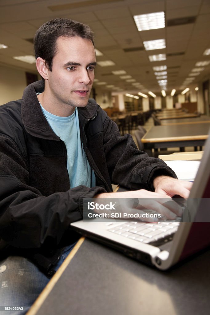 Collège étudiant à l'aide d'un ordinateur portable dans la bibliothèque de l'école recherches - Photo de 20-24 ans libre de droits