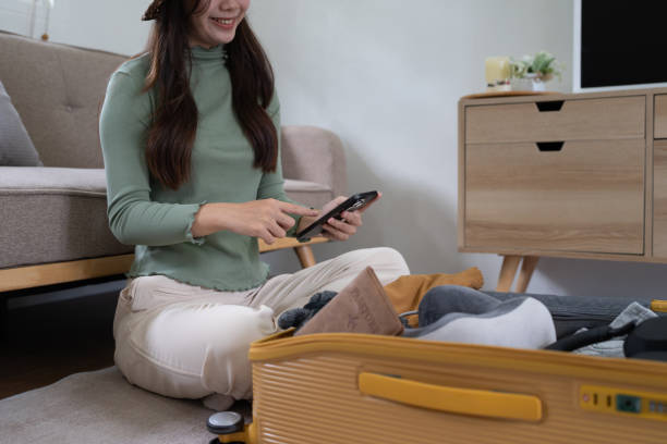 mulher jovem feliz com celular reservando férias na agência de viagens ou fazendo reserva de hotel on-line - national cash register - fotografias e filmes do acervo