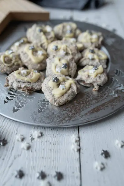 Delicious macaroons with ground almonds, chopped almonds and poppy seeds. Delicious and tasty christmas cookies on a silver plate on decorated table.