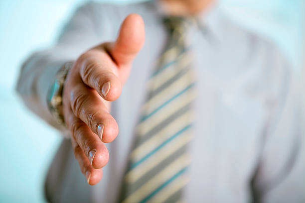 Businessman is going to shake your hand. Shallow depth of field, focus on finger-tips.