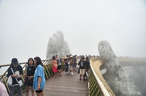 Danang, Vietnam - June 27, 2023: The Golden Bridge is lifted by two giant hands in the tourist resort on Ba Na Hill