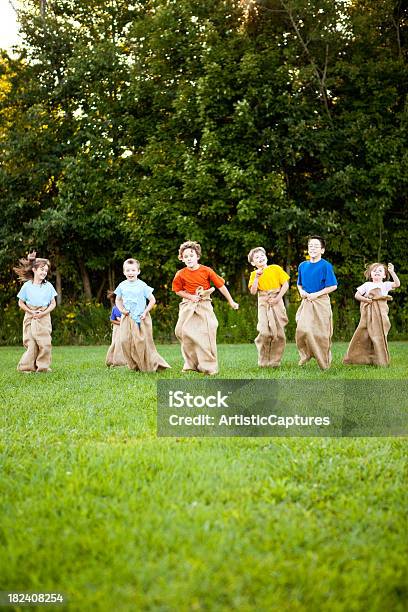 Happy Children Having A Fun Potato Sack Race Outside Stock Photo - Download Image Now