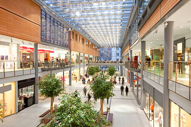 Elegant Shopping Mall Image taken inside a shopping mall. There are lots of people walking around going to stores, buying things and consuming food and beverages. There are two floors with shops and boutiques. The ceiling is glass. The architecture is very modern and new and the general feel of the images is bright, clean, safe and positive. berlin photos stock pictures, royalty-free photos & images