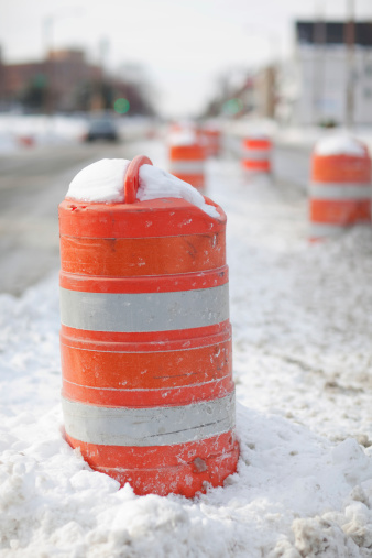 An orange traffic cone in the snow covered street